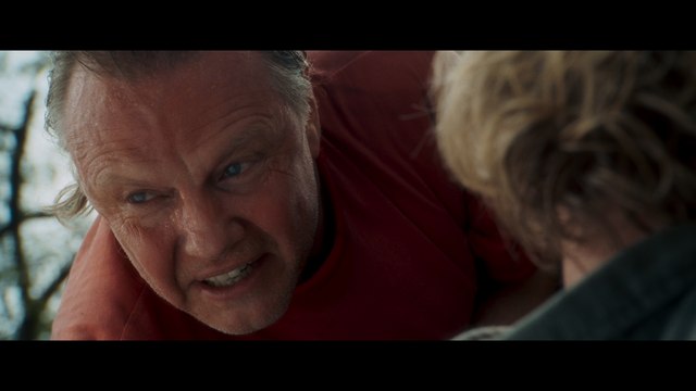 A dramatic scene featuring a man in a red shirt, expressing intense emotions while interacting with another character off-screen.