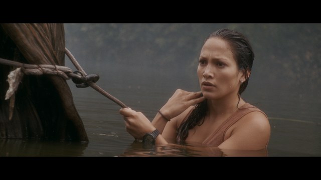 A woman is partially submerged in water, looking concerned while gripping a rope tied to a nearby structure.