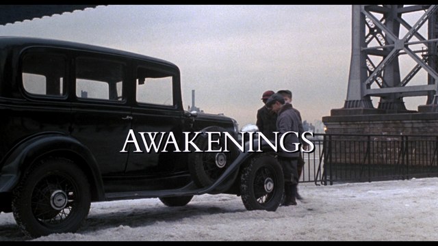 Scene from the movie 'Awakenings' featuring an old black car parked near a bridge, with three individuals standing beside it in a snowy environment.
