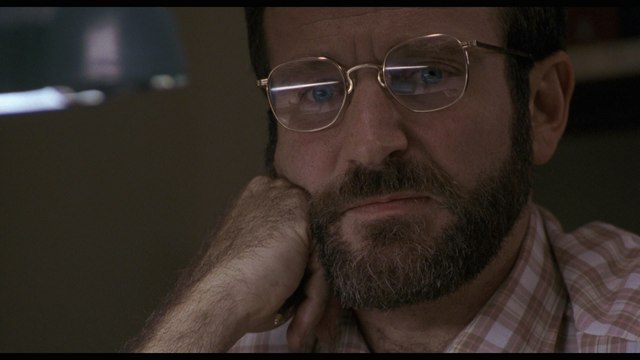 Close-up of a man with glasses and a beard, looking thoughtfully with his hand on his chin.