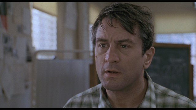 Close-up of a man with short, tousled hair, wearing a plaid shirt, looking concerned in an indoor setting.