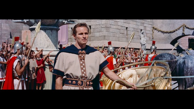 A scene from the film showing two male characters, one in a futuristic helmet and uniform, smiling while the other appears tense, conveying a sense of intrigue.