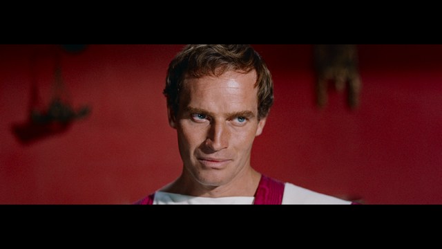 Close-up of a man with a concerned expression, wearing a suit, with a blurred background suggesting an indoor setting.