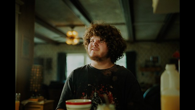 A close-up of a person's hand holding a crumpled newspaper with the headline "Mooby's: Creating an Empire Out of Simplicity" and a graphical chart showcasing growth, titled "It was a very Good YEAR."