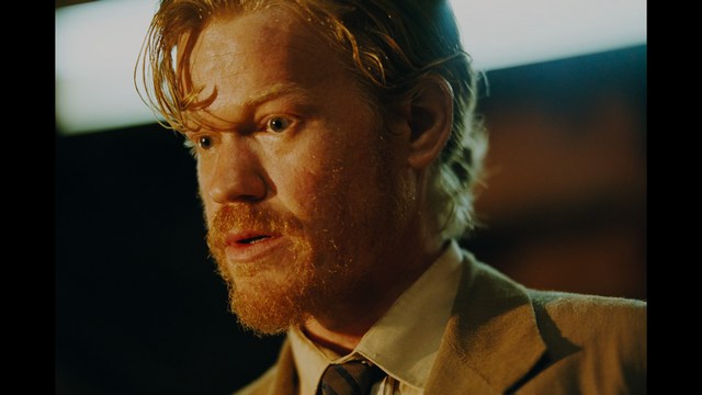 Two characters sitting in a diner, one wearing a blue beanie with 'SNOOGANS' and the other wearing a cap, both looking intently at something off-screen.