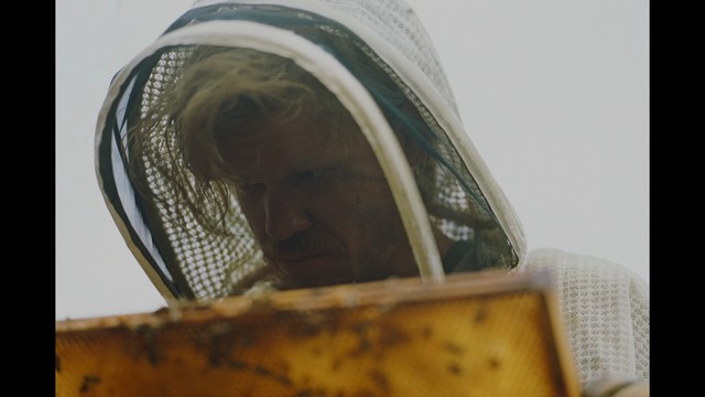 Two men are engaged in conversation at a colorful playground with bright slides in the background.