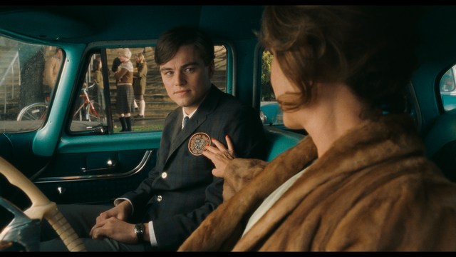 A group of people standing in a church, with a focus on a woman in a striped blazer looking up, while others are holding books or looking ahead.