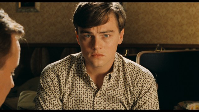 Three young individuals sitting together, two holding hockey sticks, with a casual and intense expression in a domestic setting.