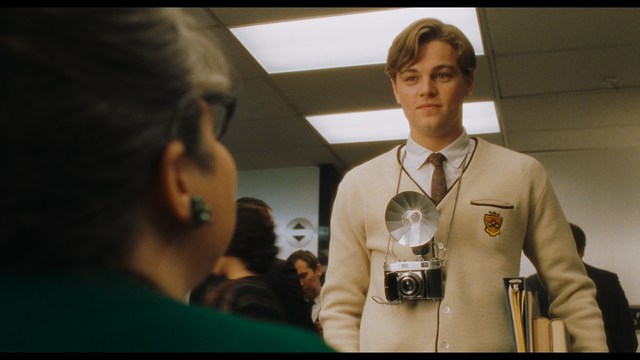 Two characters sitting in a diner, one wearing a blue beanie with 'SNOOGANS' and the other wearing a cap, both looking intently at something off-screen.
