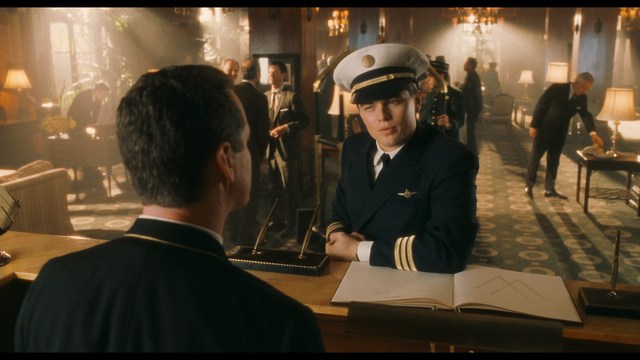 A woman with dark hair and a neutral expression sitting in a retro diner setting.