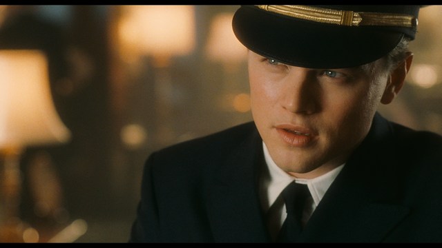 A young man pointing a handgun while seated in a bus, showcasing an intense expression.