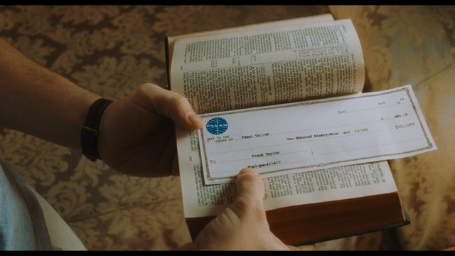 A scene from a movie featuring three characters standing on a bridge with a lush green landscape in the background.