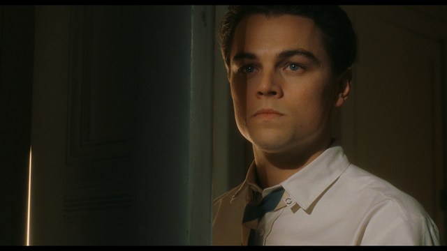 A shocked man with long hair and a baseball cap sitting in a bar, looking surprised.