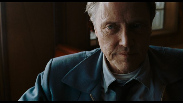 Aerial view of futuristic skyscrapers with cars driving vertically up the side of a building, showcasing a modern urban landscape.