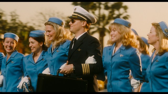 A scene from the film showing two male characters, one in a futuristic helmet and uniform, smiling while the other appears tense, conveying a sense of intrigue.
