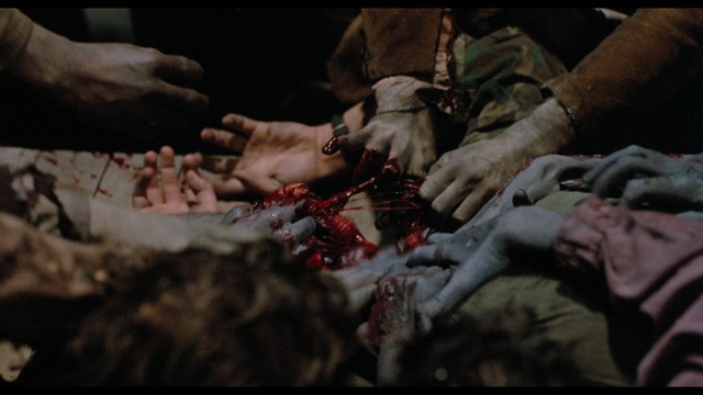 A close-up of multiple hands reaching towards a bloody and gruesome scene, with visible wounds and splattered blood.