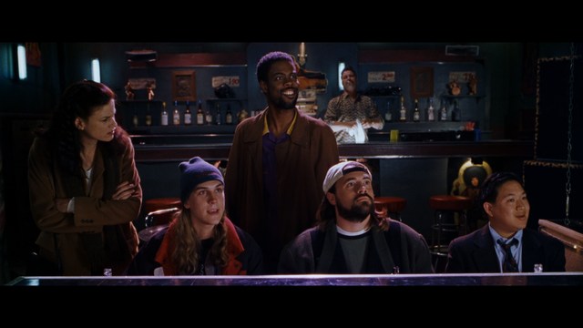 A scene featuring five characters in a bar setting, with a focus on their expressions and interactions. The backdrop includes bar shelves with bottles and a bartender visible in the background.