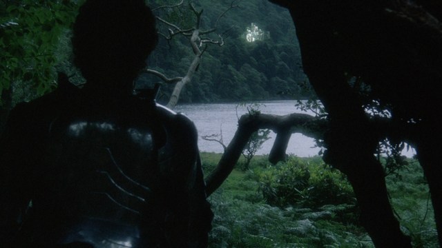 A scene from a film featuring two characters having a conversation in a greenhouse filled with various plants.