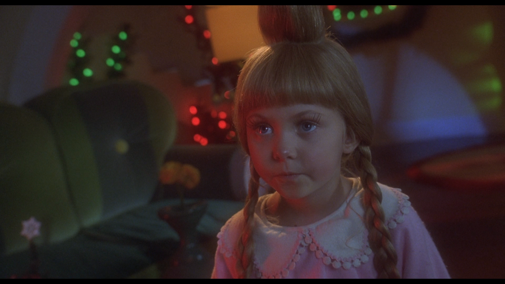 Two male characters in a movie scene, standing indoors near a doorway, with a blurred background of a waiting area.