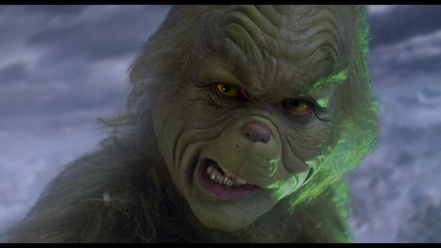 A scene featuring a man dressed as a cardinal, standing in front of a building with signs related to Catholicism.