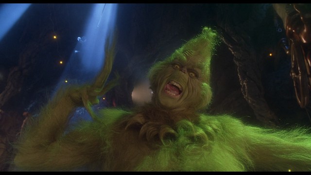 A close-up of a woman with dark hair and a serious expression sitting in a diner, with blurred background elements suggesting a busy atmosphere.