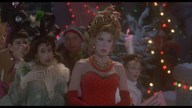 Two men engaged in conversation in a scene from a movie, set against a colorful playground background.