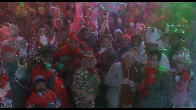 A scene from a film showing five characters in a bar setting, with a colorful background and a bartender visible in the back.