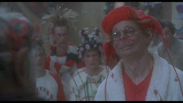 A man wearing a white suit and a fedora hat, looking surprised or upset, stands in a store with various products displayed in the background.