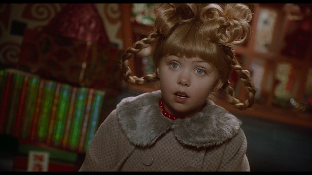 Four anthropomorphic turtles in ninja attire stand in a dimly lit room, while a humanoid character with fur sits nearby.