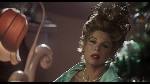 A close-up shot of a man with a distressed expression, featuring dark hair and wearing a blue hoodie, against a softly lit background.