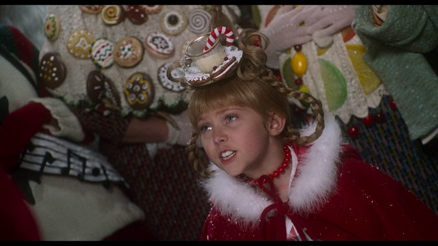 Two characters sitting in a diner, one wearing a blue beanie with 'SNOOGANS' and the other wearing a cap, both looking intently at something off-screen.
