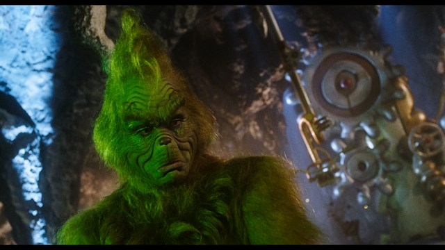 A scene from a movie featuring three characters standing on a bridge with a lush green landscape in the background.