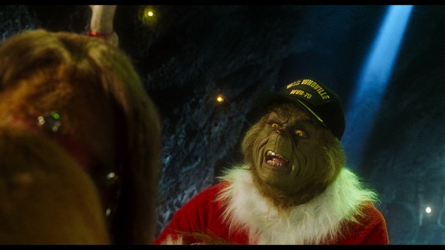 A man with short hair and a beard sits at a table, looking surprised or excited while holding a bottle.