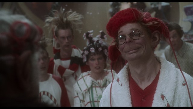 A close-up shot of a man wearing a white suit and a white hat, looking intently at someone in a retail store filled with merchandise.