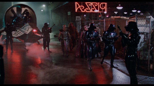 A group of characters in futuristic gear, looking tense and alert, possibly in a sci-fi setting.