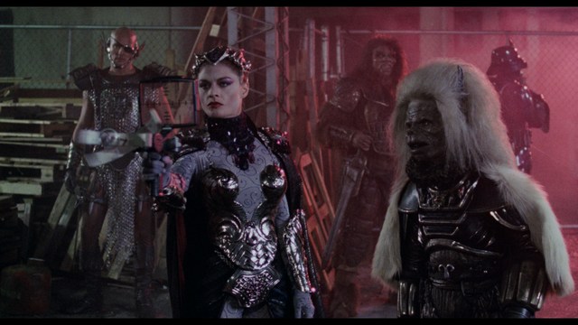 A scene from the film showing two male characters, one in a futuristic helmet and uniform, smiling while the other appears tense, conveying a sense of intrigue.