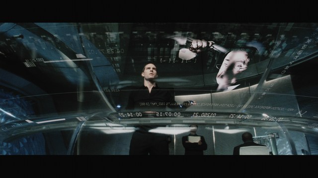 Two male characters sitting in a waiting area, one wearing a black jacket and the other in a maroon hoodie, with popcorn in hand.