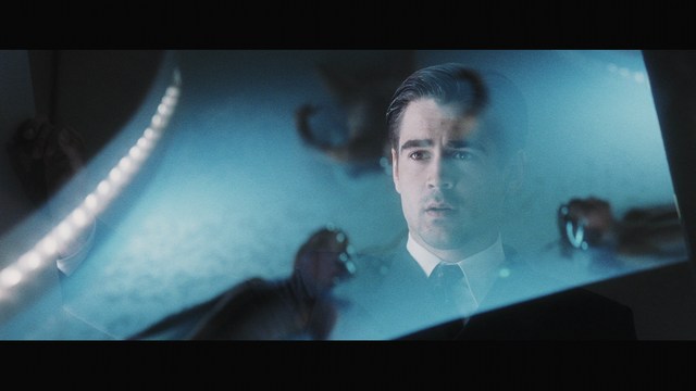 Three teenagers sitting on the floor, each holding a hockey stick, with two laughing and one looking serious. The background features a room with neutral-colored walls.