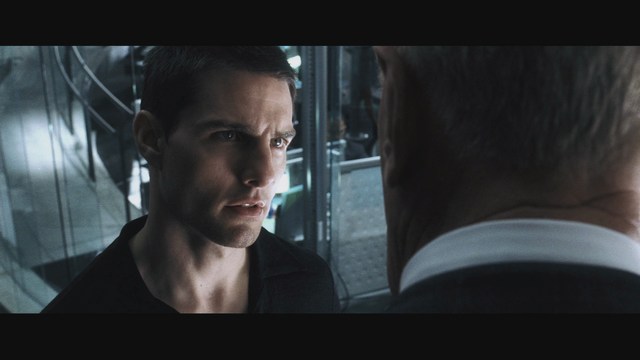 Two men engaged in conversation in a scene from a movie, set against a colorful playground background.