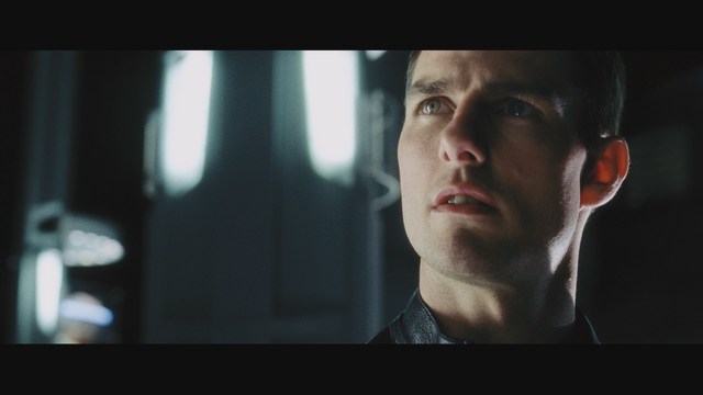 A man wearing a white suit and hat appears to be having a serious conversation in a retail store, with various products displayed in the background.