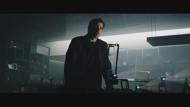 A woman sitting at a restaurant table, resting her chin on her hand while reading a newspaper.