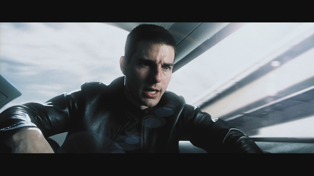 A scene featuring a man sitting with his arms crossed, looking away, and a woman with a concerned expression, seen in a dimly lit bar setting.