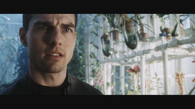 Close-up of a man in a greenhouse, looking concerned, with plants in the background.