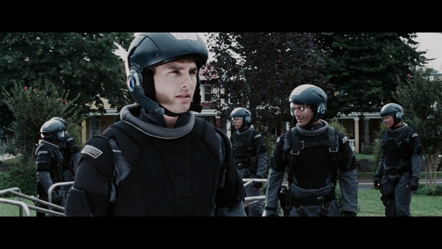 A woman with dark hair and a neutral expression sitting in a retro diner setting.