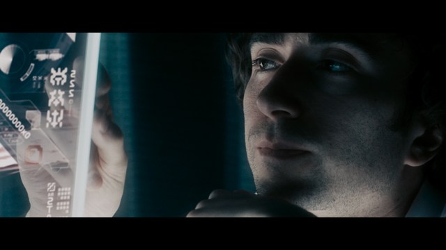 A scene from a movie featuring three characters standing on a bridge with a lush green landscape in the background.