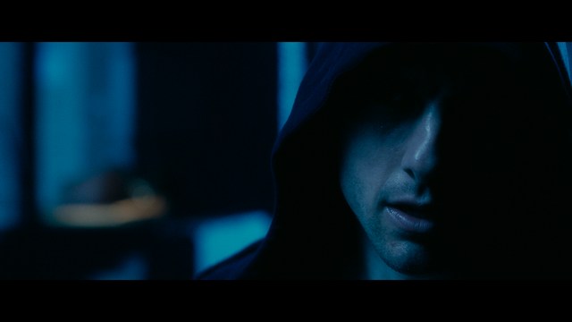 A worried woman stands on a deserted road, looking shocked or distressed as she gazes into the distance.