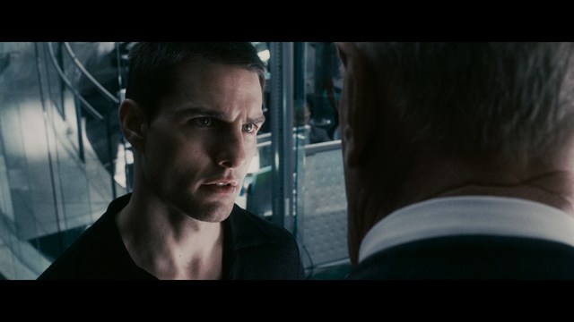 Two men are engaged in conversation at a colorful playground with bright slides in the background.