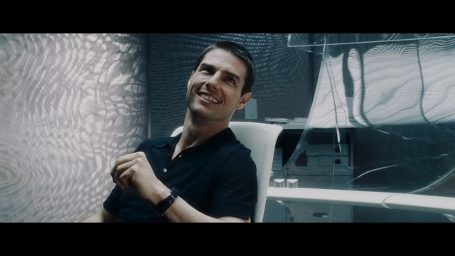 A man with short hair and a beard sits at a table, looking surprised or excited while holding a bottle.