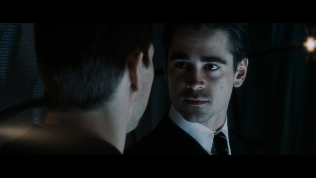 Close-up of a woman with long black hair sitting in a restaurant, looking concerned. A colorful painting is visible in the background, along with red bar stools.