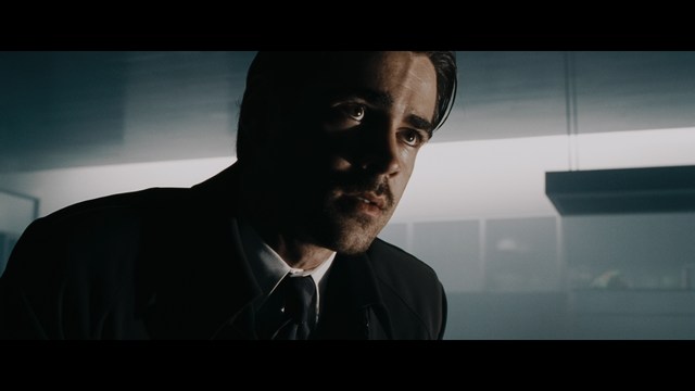 A man with dark, styled hair and a subtle smile seated at a restaurant table, with blurred diners in the background.